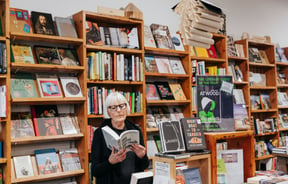 A woman reading a book behind a desk.