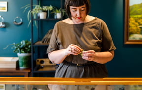 A close up of a woman wearing a blunt hair cut holding a ring.