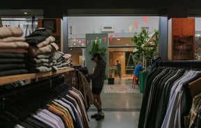 Looking between clothing racks towards the entrance to the Stencil store in The Colombo mall.