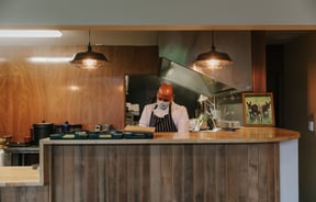 Chef of Three Donkeys preparing food behind the counter.