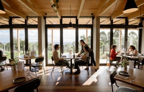 Interior of Tussock Hill restaurant with customers dining against the panoramic windows that look out over the Christchurch Port Hills.