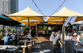 Lots of people sitting around tables at Smash Palace Christchurch on a sunny day.