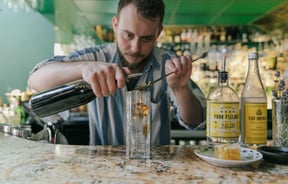 A bar man making a gin cocktail at the counter inside Gin Gin Christchurch.