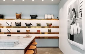 Leather bags on display on wooden floating shelves.