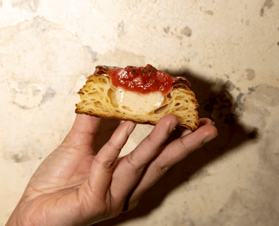 Someone holding up a pastry cut in half with jam and custard in the middle