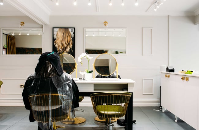 A client getting their hair done inside the brightly lit hair salon.