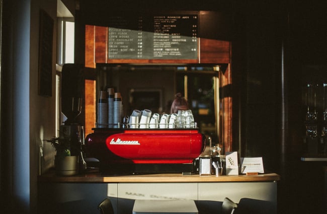 A barista working behind a bright red coffee machine.