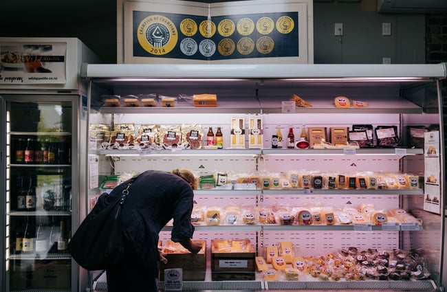 A woman browsing the cheese inside the shop at at Barrys Bay Cheese, Akaroa.