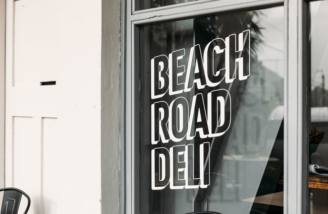 A white 'Beach Road Deli' sign painted on a window.