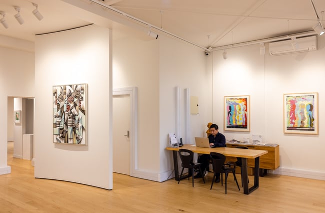 A man working at a desk in a gallery.