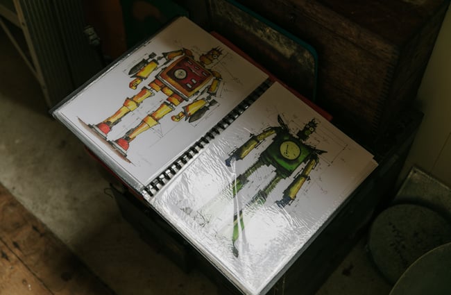 A close up of hand drawn and painted robots in a clear file on a table.