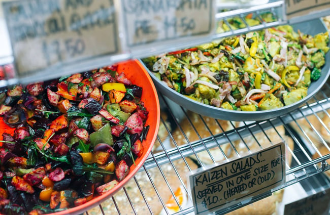 Bowls of coloured salads in a cabinet.