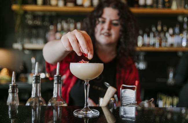 A female bartender making a cocktail.