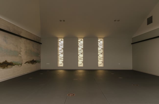 An empty yoga studio with light streaming in through windows.