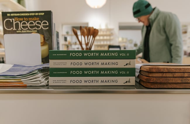 A close up of green and white cookbooks stacked.
