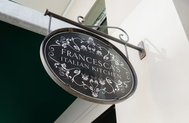 Close up of an exterior wall sign that says 'Francesca's Italian Kitchen'.