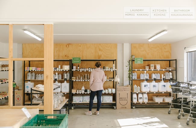 A lady browsing through the eco store products on black shelving.