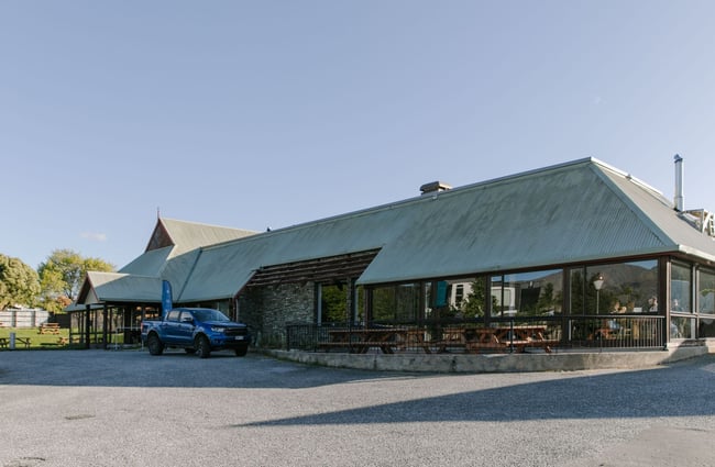 The exterior of the wooden Hawea Hotel with an outdoor seating area.