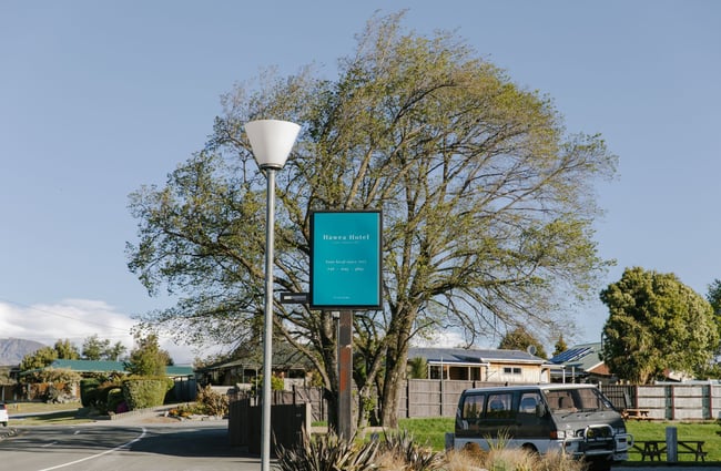 The blue sign for the Hawea Hotel on the roadside.