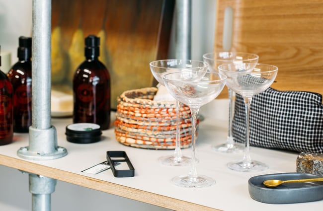 Champagne coupes on display on a white shelving unit.