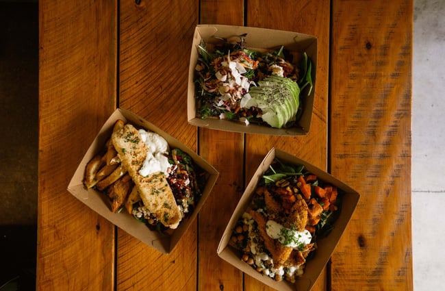 Flatlay image of three different takeaway salads on the wooden counter at Herba Gourmet in Christchurch.