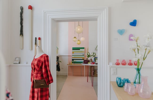 A pink and white room showcasing local art and clothing  at Inc Design Ōamaru.