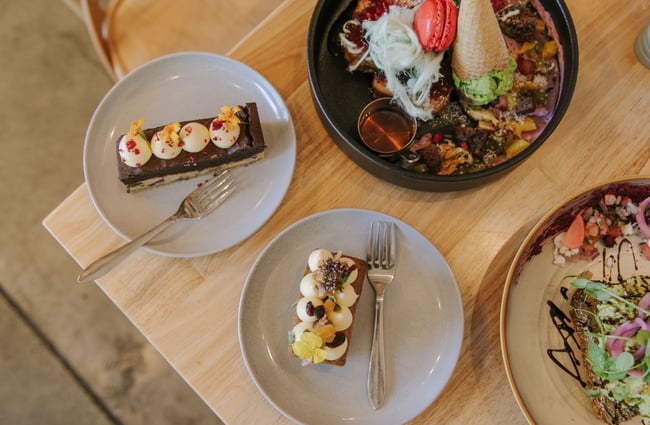 A flatly of savoury dishes and desserts on a wooden table.
