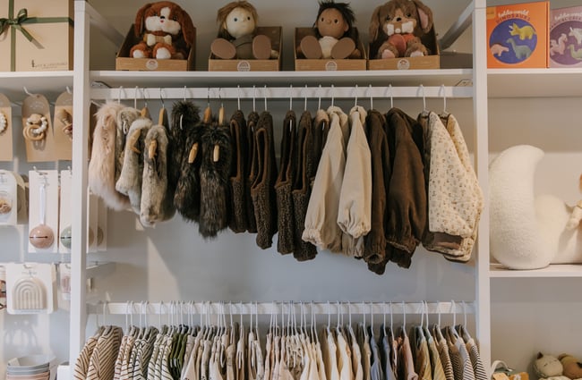 A close up of little brown jackets and coats hanging on a high rack.
