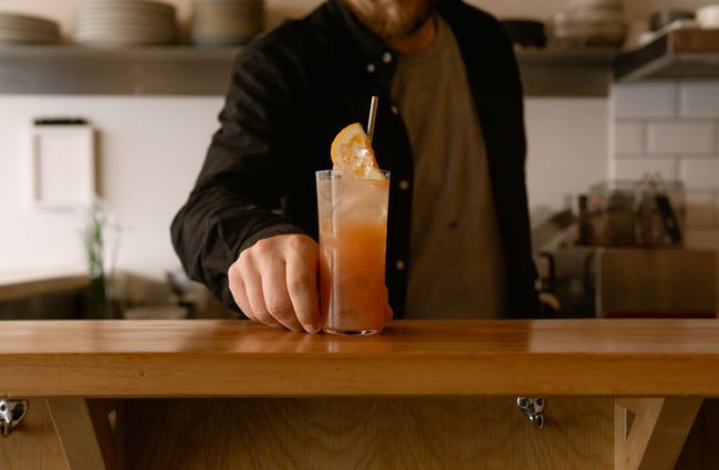 A man holding a cocktail on a counter.