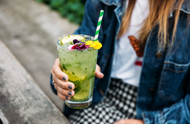 A hand holding a green cocktail.