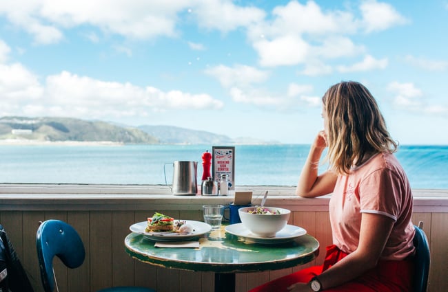 A woman looking out towards the ocean from a seat inside Maranui cafe Wellington.