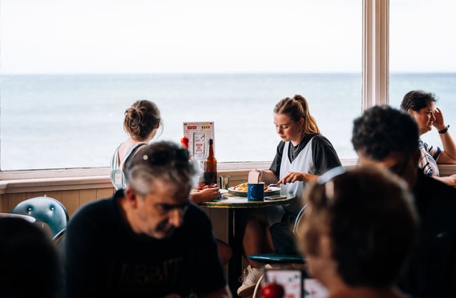People dining by a large window inside Maranui cafe Wellington.