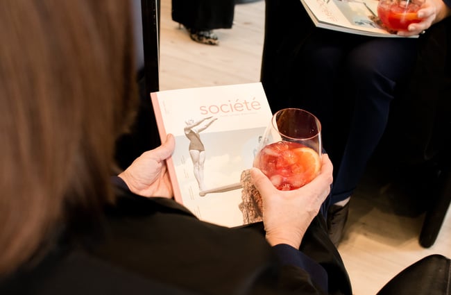 Close up of a woman reading Societe magazine and holding cocktail at Mod's Hair in Merivale.