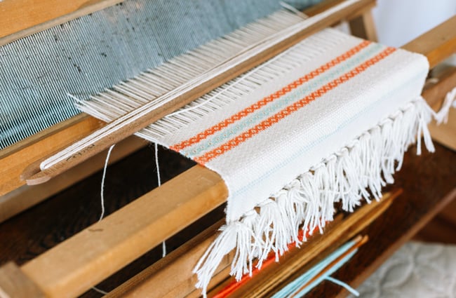 Close up of fabric being made on loom.