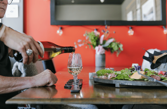 Wine being poured into a glass in the Pembroke Wines & Spirits tasting room in Wānaka.