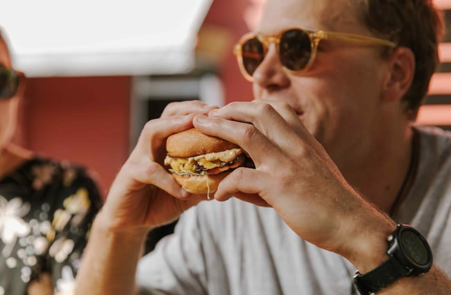 A close up of a man holding a burger.