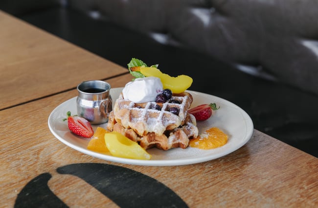 Close up of waffle with cream and fruit.