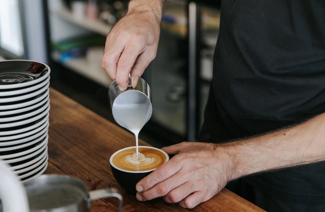 Man making a flat white with steamed milk.