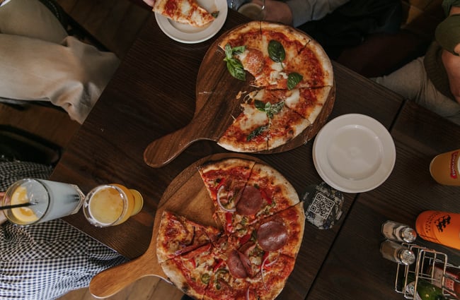 Two cooked pizzas on a table.