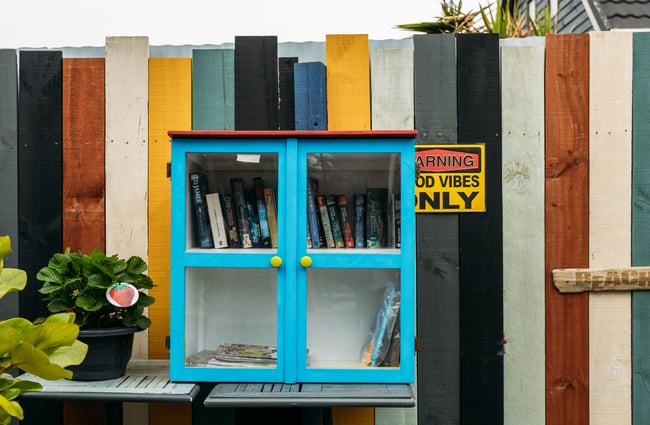A small blue community library box with glass doors.