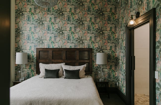 A bedroom with green and pink wallpaper.