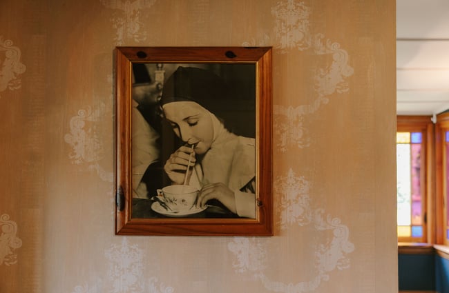 Old photograph of a nun sipping a drink through a straw at The Old Vicarage, Christchurch.