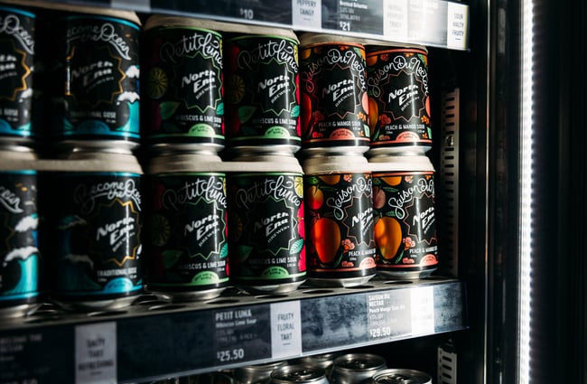 A close up of craft beers in cans in a fridge.