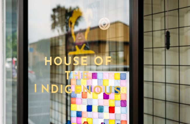A close up of a sign on a door that says 'The House of The Indigenous'.