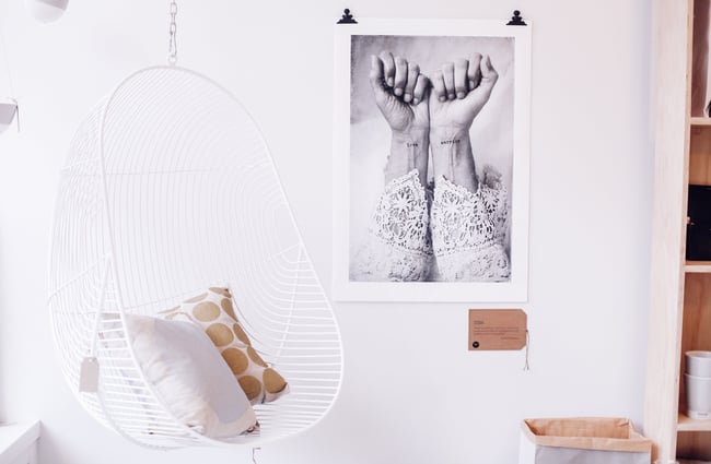 White hanging chair next to a black and white print.