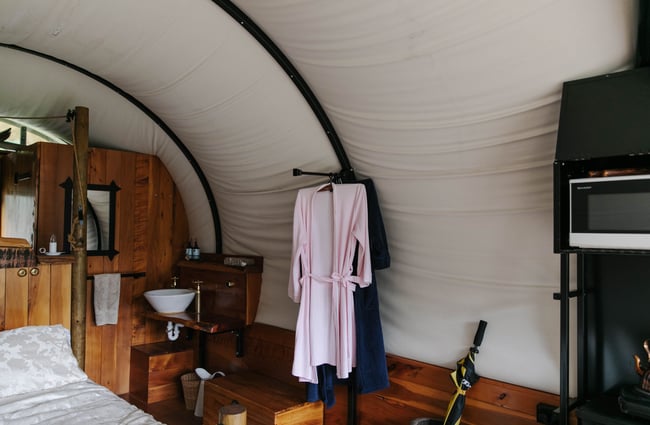 Inside wooden wagon with robes hanging up.