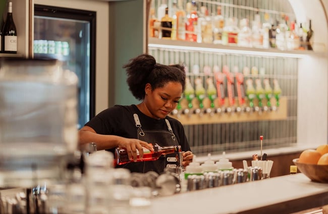 A woman pouring a drink behind a bar at Willis Lane.