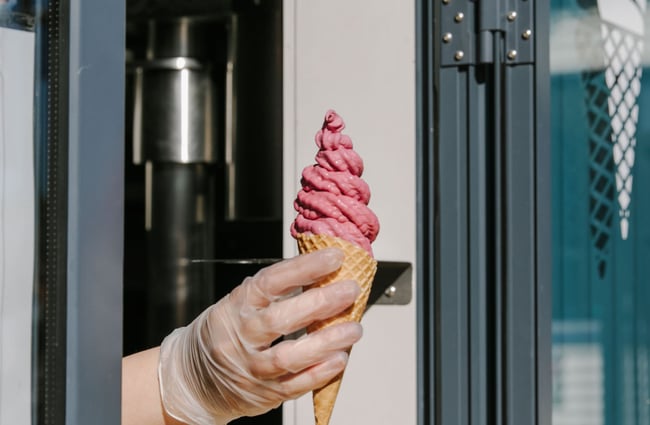 Handing an ice cream to a customer out of a hatch at Alberta's, Māpua Wharf.