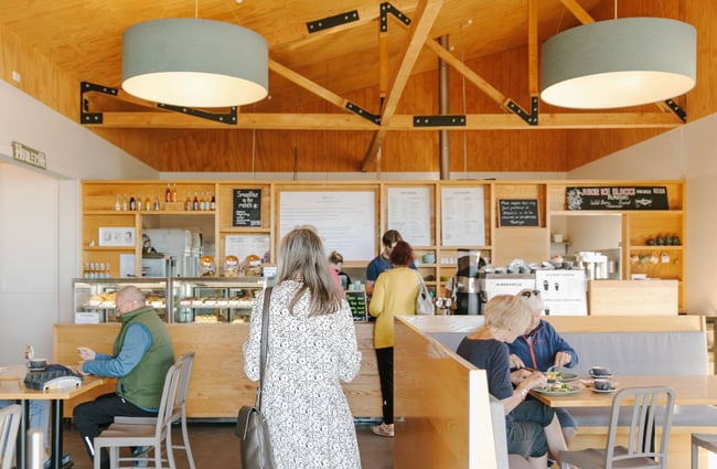 Woman walking inside Alberta's with people dining at tables on either side.