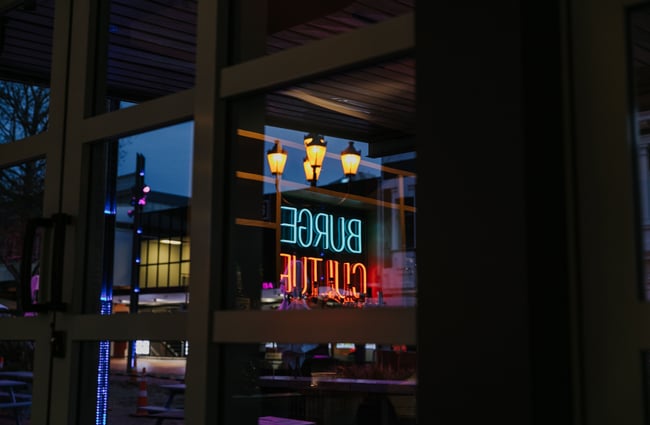 Burger Culture neon sign reflected in window.